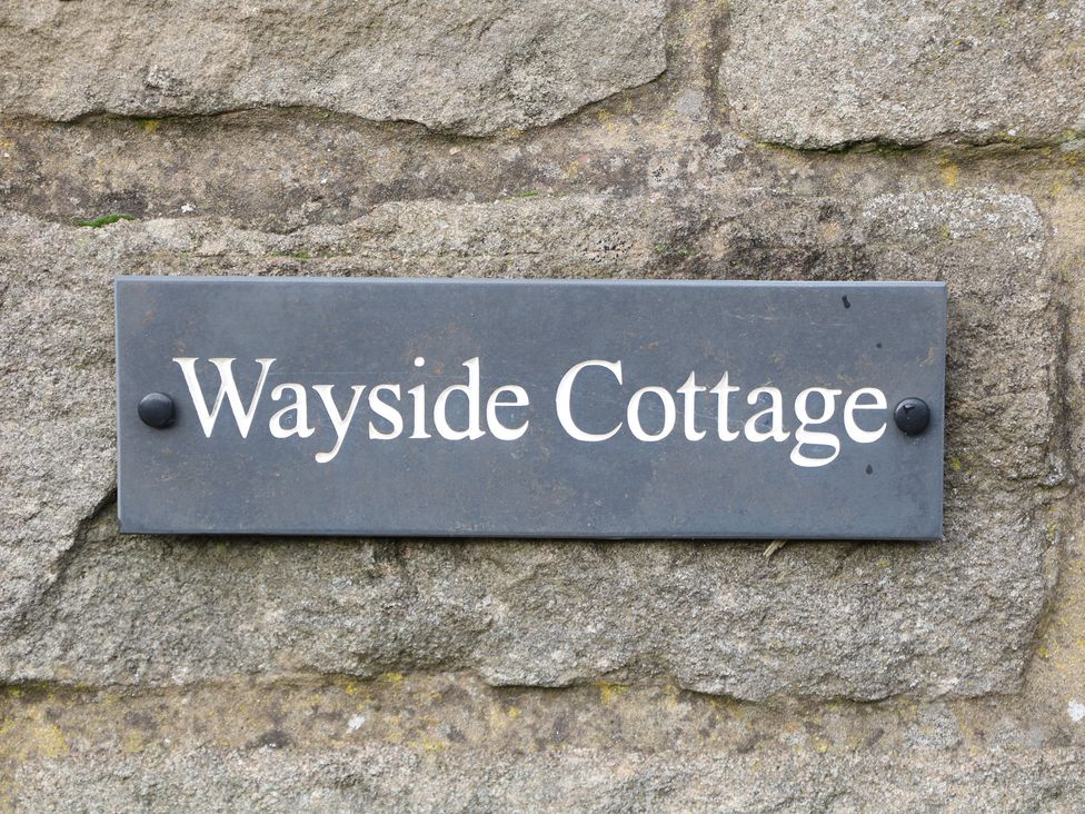 A sign for Wayside Cottage fixed to a stone wall at Wayside Cottage at Wayside Farm Matlock