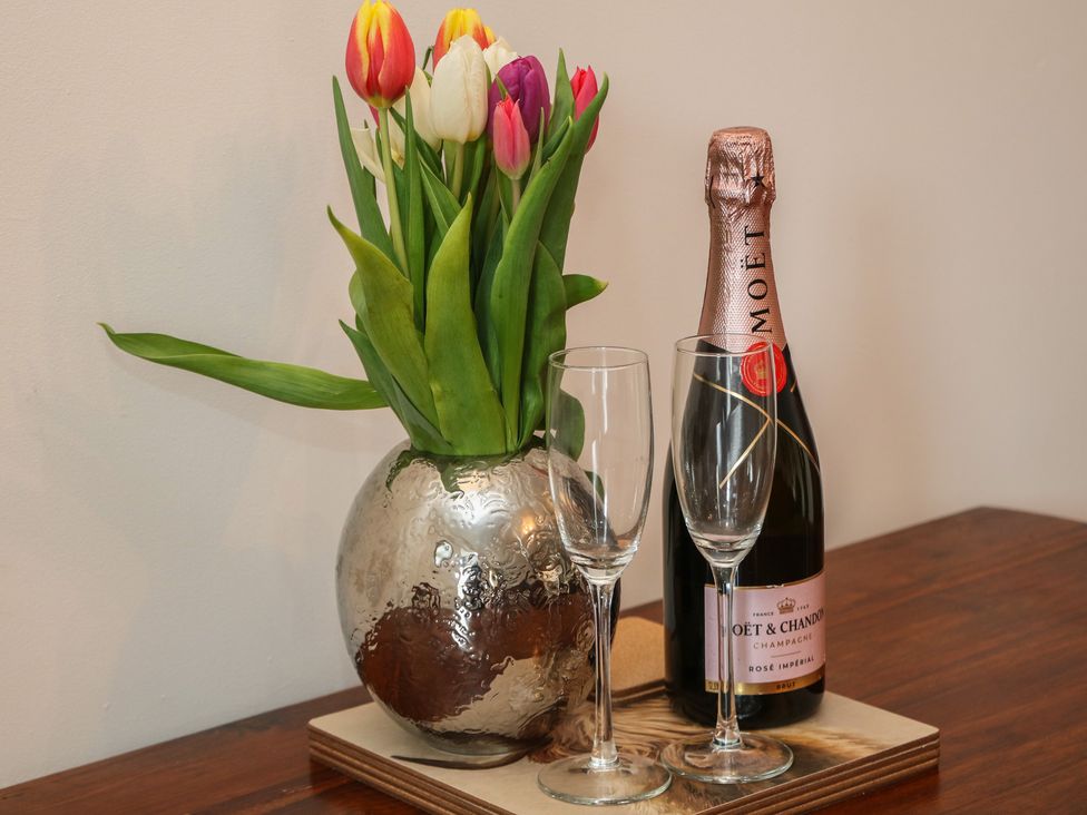 A living room with flowers and champagne on a table at Wayside Cottage at Wayside Farm, Matlock