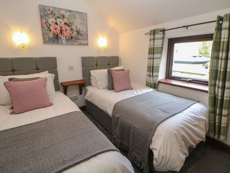 A bedroom with two beds and a window at Wayside Cottage at Wayside Farm, Matlock