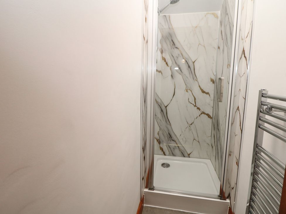 A shower with marble panels and a towel radiator at Wayside Cottage at Wayside Farm, Matlock
