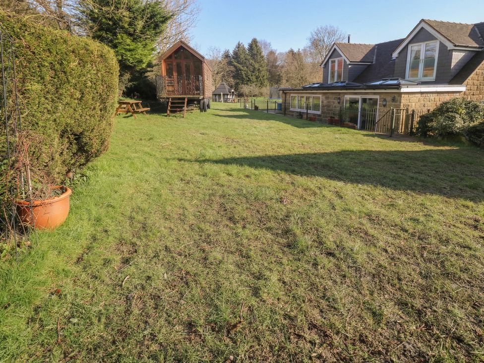 A garden with grass and a wooden building at Wayside Cottage at Wayside Farm Matlock