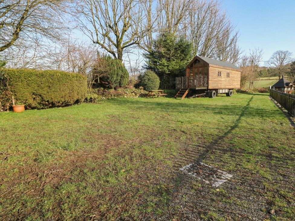 An outdoor area with a wooden cabin, table, and trees at Wayside Cottage at Wayside Farm, Matlock