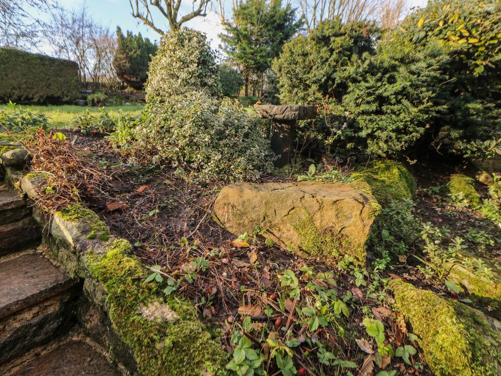 A garden area with plants and a stone at Wayside Cottage at Wayside Farm in Matlock