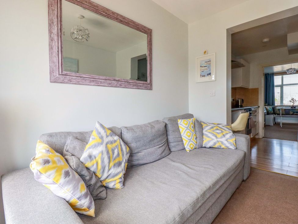 A living room with a sofa and cushions at Tolcarne Reach in Newquay