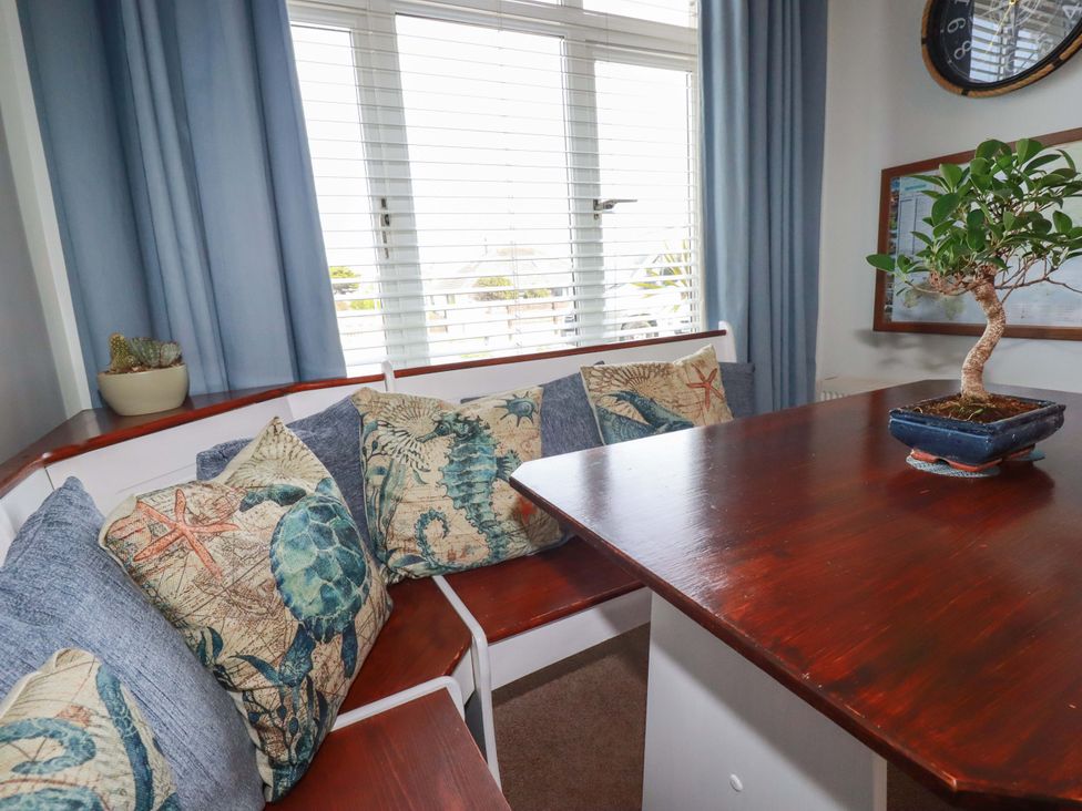 A dining room with a table and cushions at Tolcarne Reach in Newquay