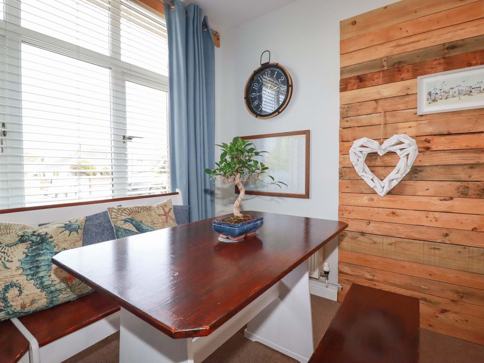 A dining room with a table and benches at Tolcarne Reach in Newquay