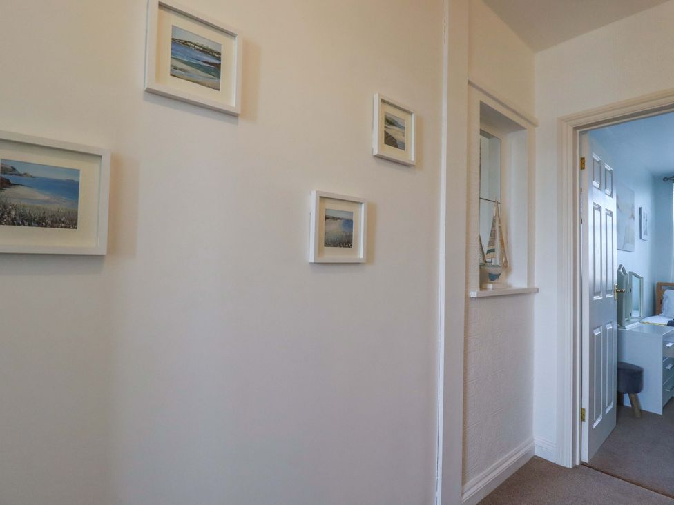 A hallway with framed pictures and a door at Tolcarne Reach in Newquay