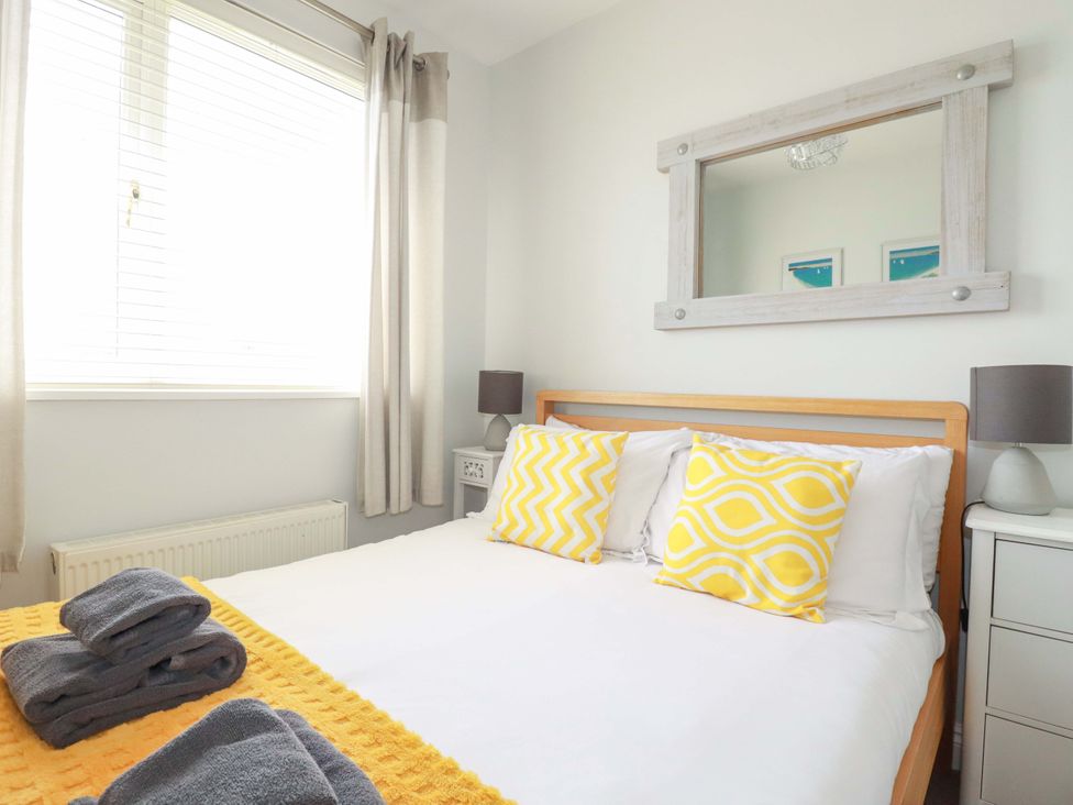A bedroom with a bed and window at Tolcarne Reach in Newquay
