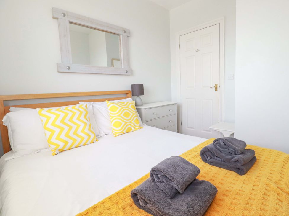 A bedroom with a bed and towels folded on the bed at Tolcarne Reach in Newquay