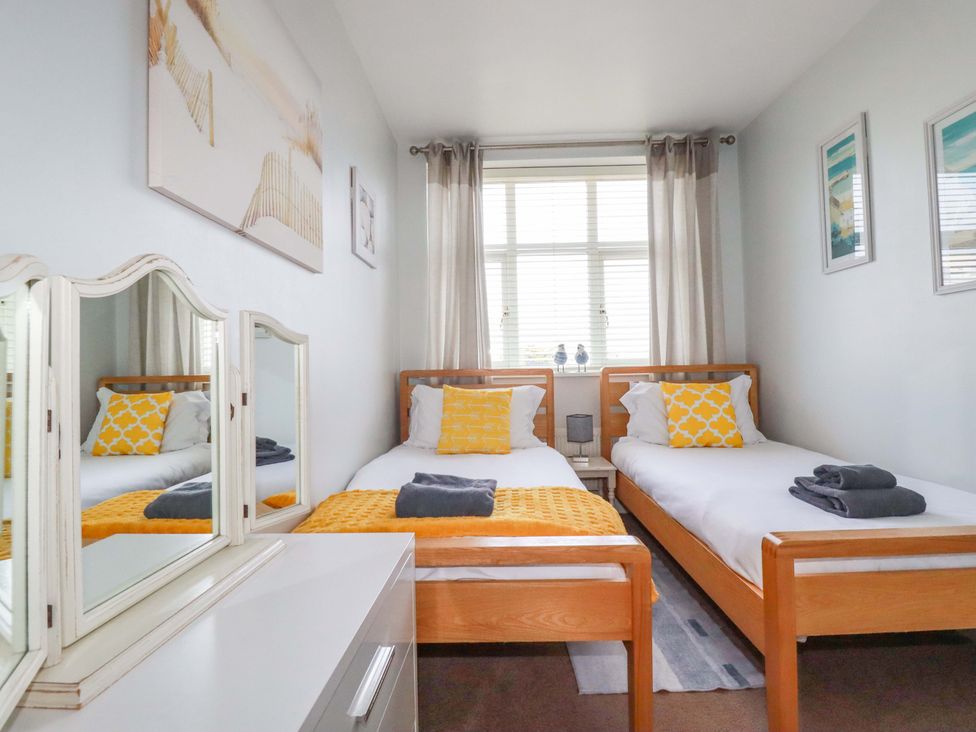 A bedroom with two beds and a mirror at Tolcarne Reach in Newquay