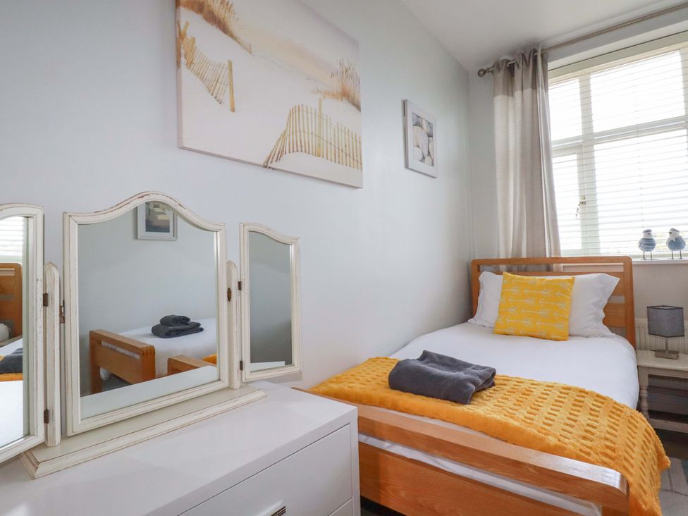 A bedroom with a single bed and a mirror at Tolcarne Reach in Newquay