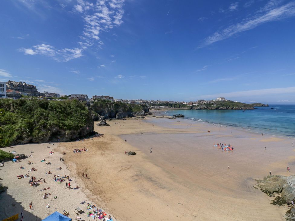 A beach with people and waves at Tolcarne Reach in Newquay