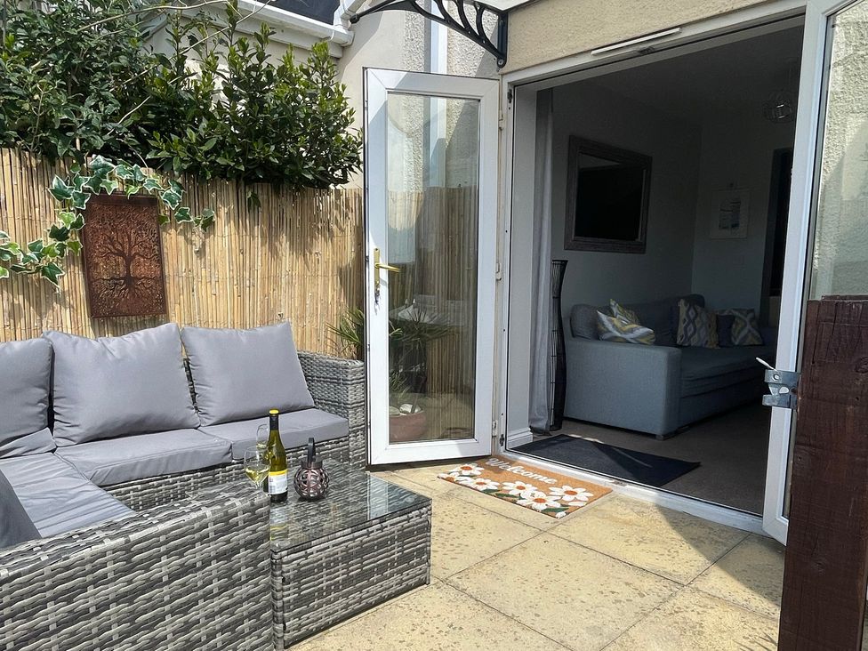 An outdoor seating area with a glass table at Tolcarne Reach in Newquay