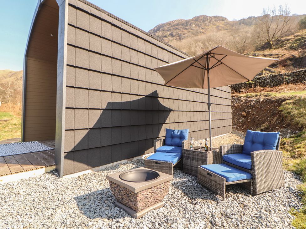 An outdoor seating area with a fire pit and armchairs at Bluebelle - Crossgate Luxury Glamping Hartsop