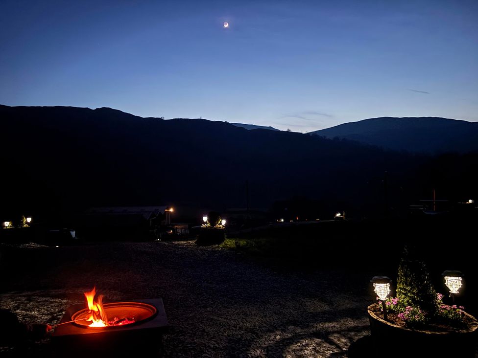 An outdoor area with a fire pit and mountains in the background at Bluebelle - Crossgate Luxury Glamping, Hartsop