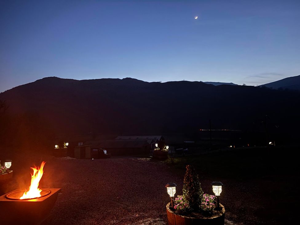 An outdoor area with a fire pit and mountains in the background at Bluebelle - Crossgate Luxury Glamping Hartsop