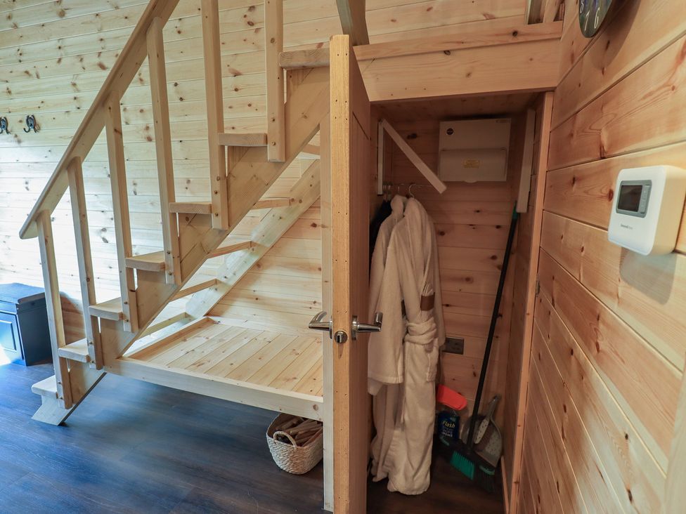 A staircase and storage area with a robe and basket at Bluebelle - Crossgate Luxury Glamping Hartsop