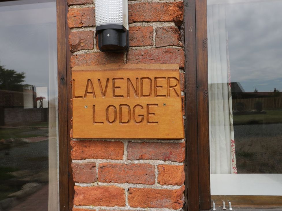 A wooden sign for Lavender Lodge on a brick wall at Lavender Lodge in Hull