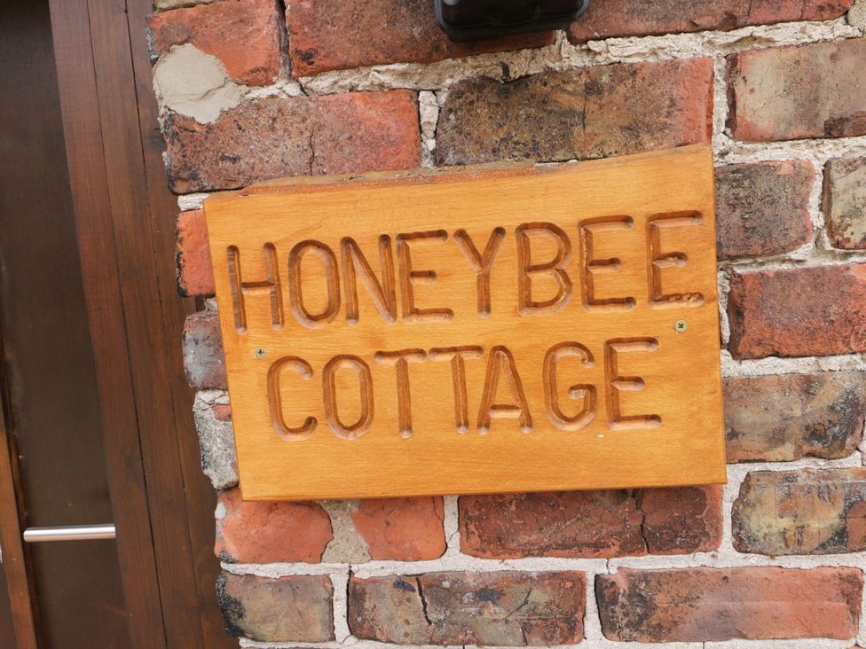 A wooden sign on a brick wall at Honeybee Cottage in Hull