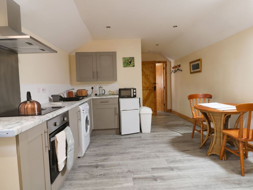 A kitchen with appliances and a dining table at Honeybee Cottage in Hull