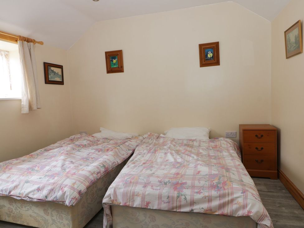 A bedroom with two beds and a bedside table at Honeybee Cottage in Hull