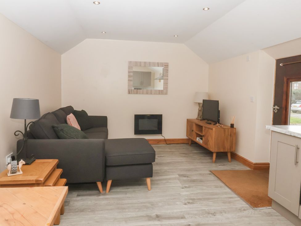 A living room with a sofa and television at Honeybee Cottage in Withernsea