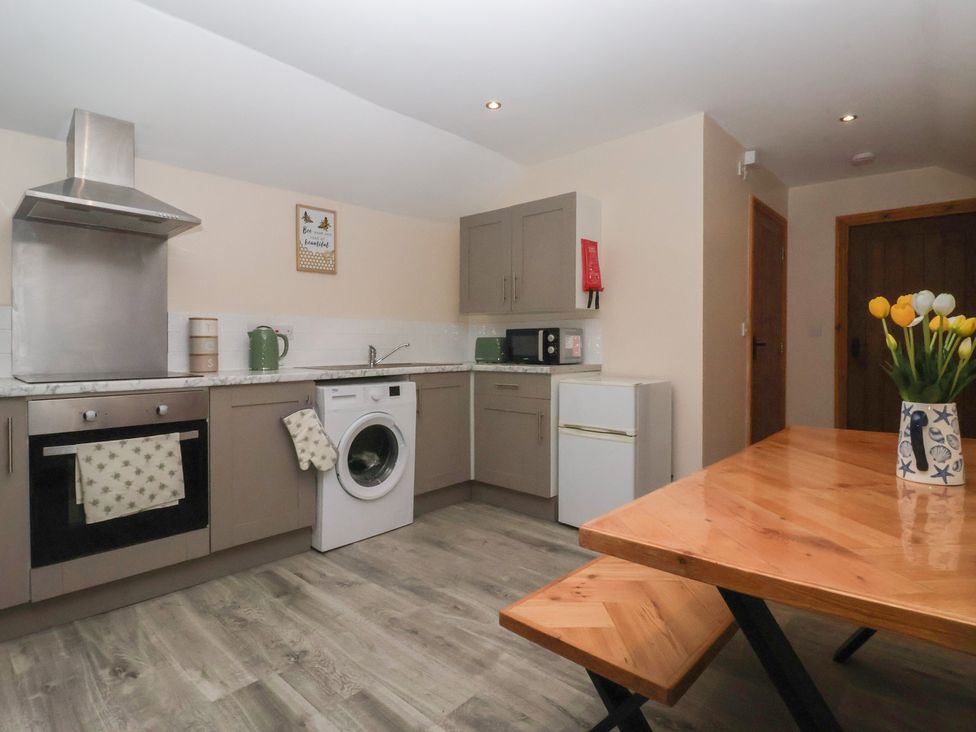 A kitchen with appliances and dining table at Honeybee Cottage in Withernsea