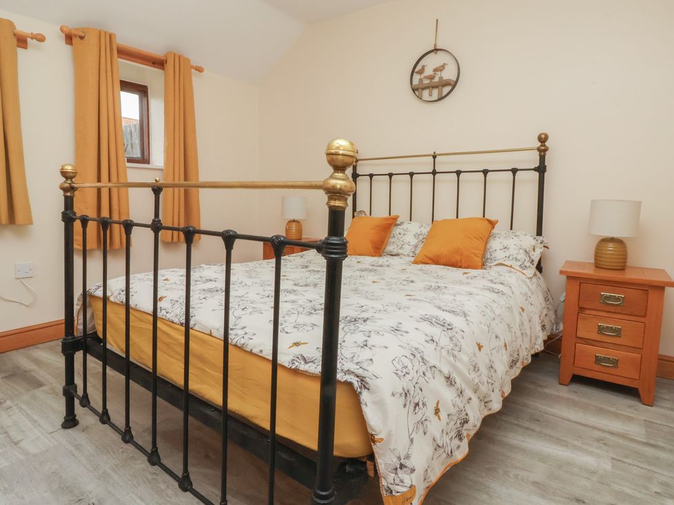 A bedroom with a bed and nightstand at Honeybee Cottage in Withernsea