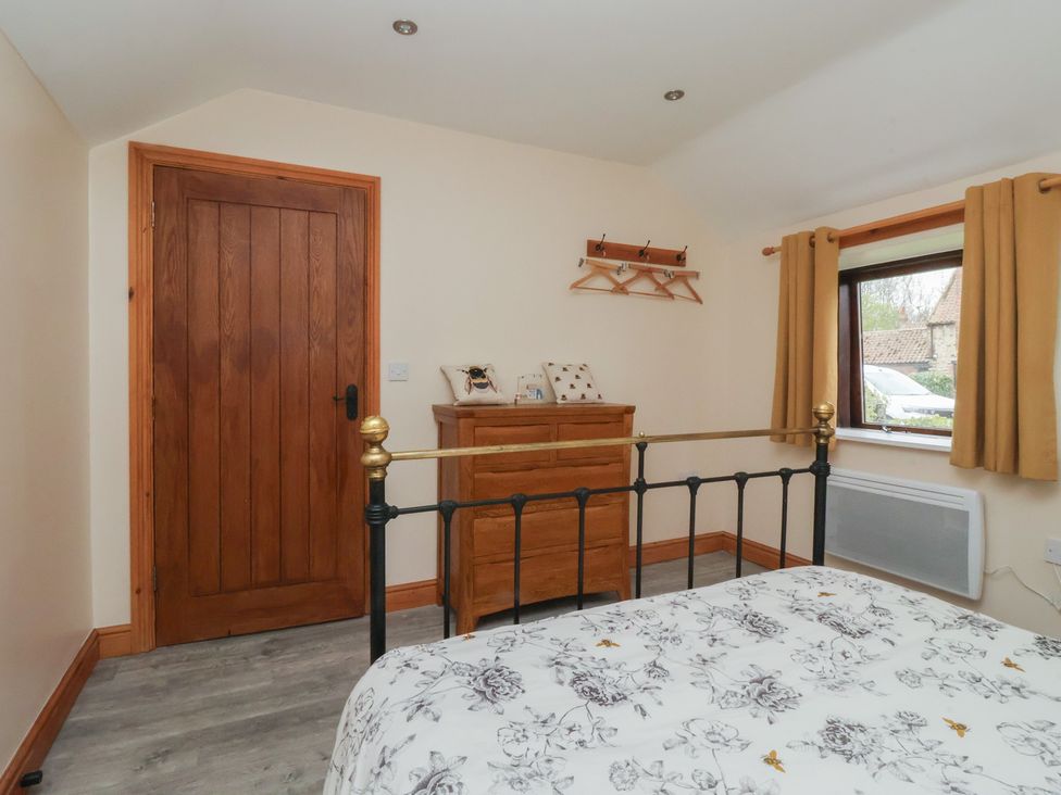 A bedroom with a bed and dresser at Honeybee Cottage in Withernsea