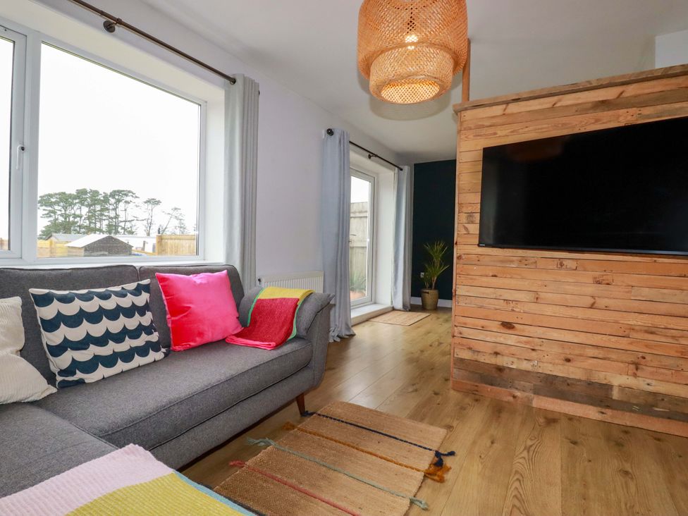 A living room with a sofa, television, and wooden features at Trelowen in Trenance