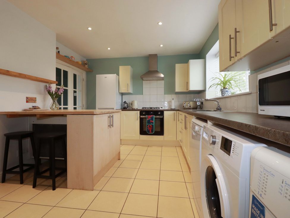 A kitchen with a stove, refrigerator, and washing machine at Trelowen in Trenance