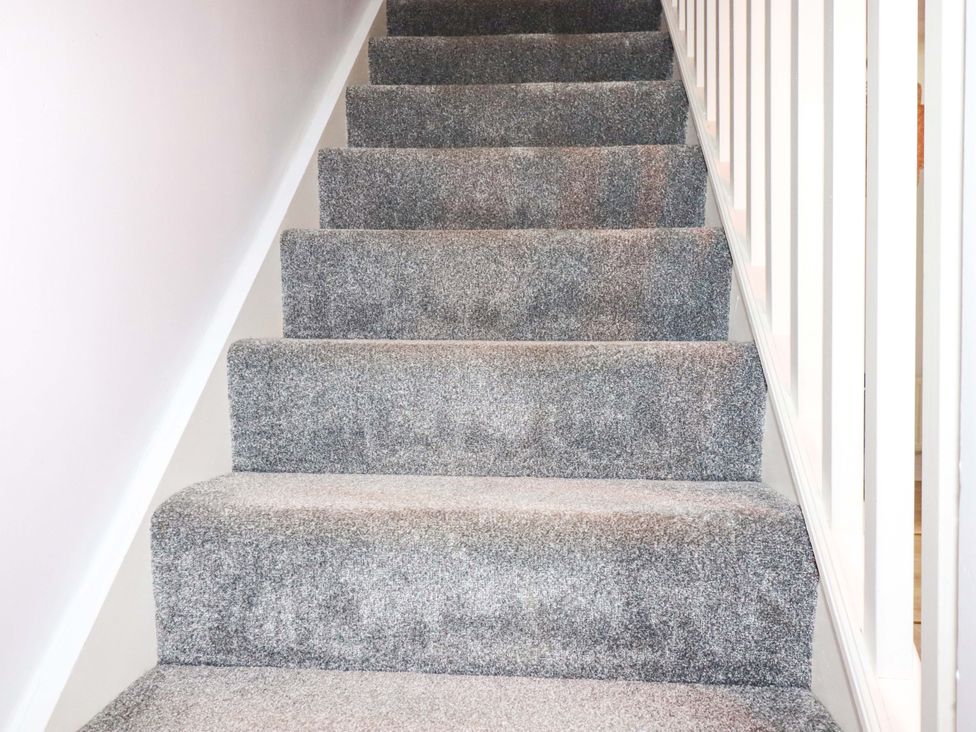 A staircase with carpet and handrail at Trelowen in Trenance