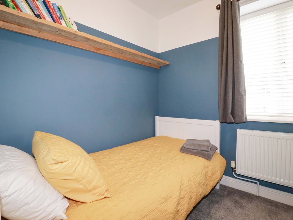 A bedroom with a bed and a shelf containing books at Trelowen in Trenance