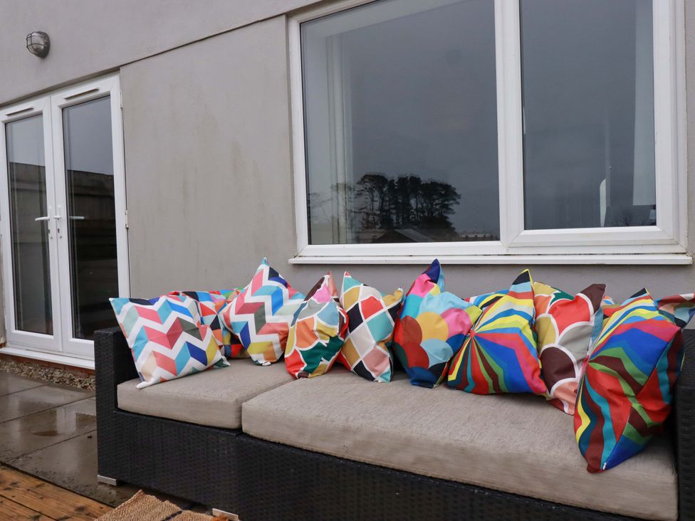 An outdoor seating area with colorful pillows and a sofa at Trelowen in Trenance