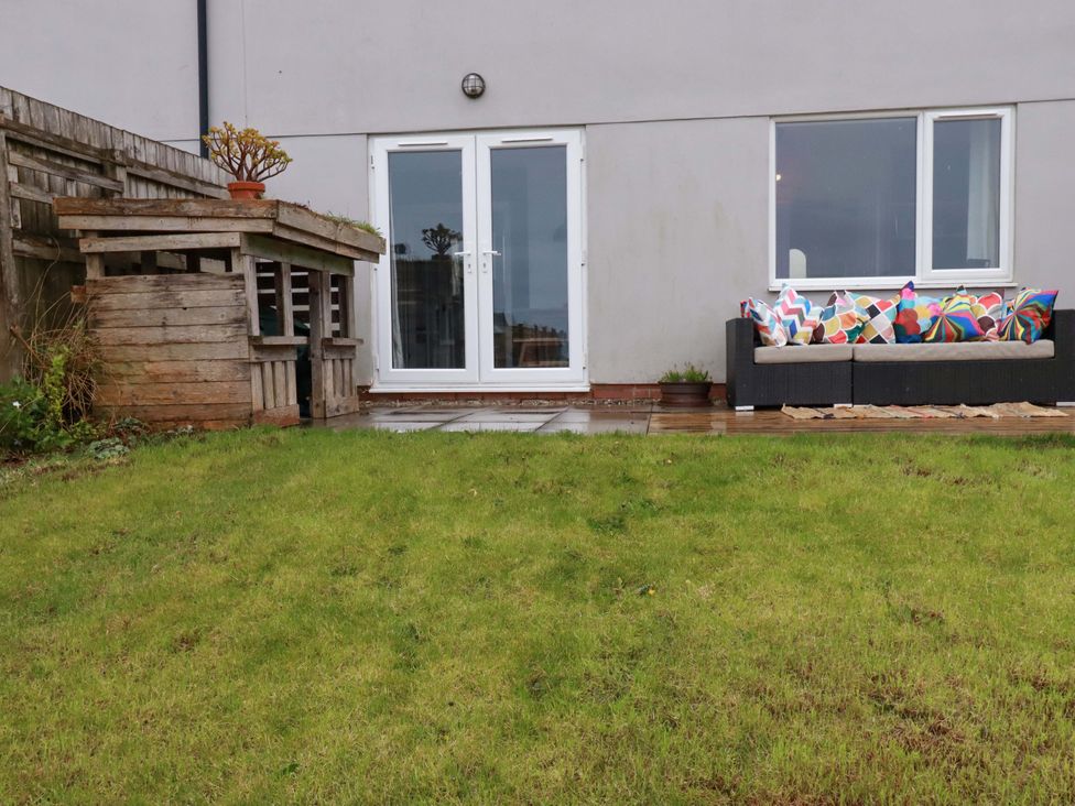 A garden with a sofa and wooden structure at Trelowen in Trenance