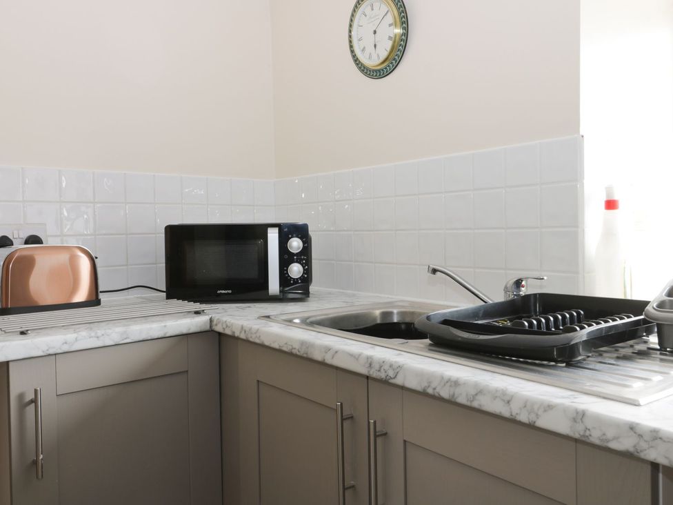 A kitchen with a toaster, microwave, sink, and dish rack at Daisy Nook in Hull