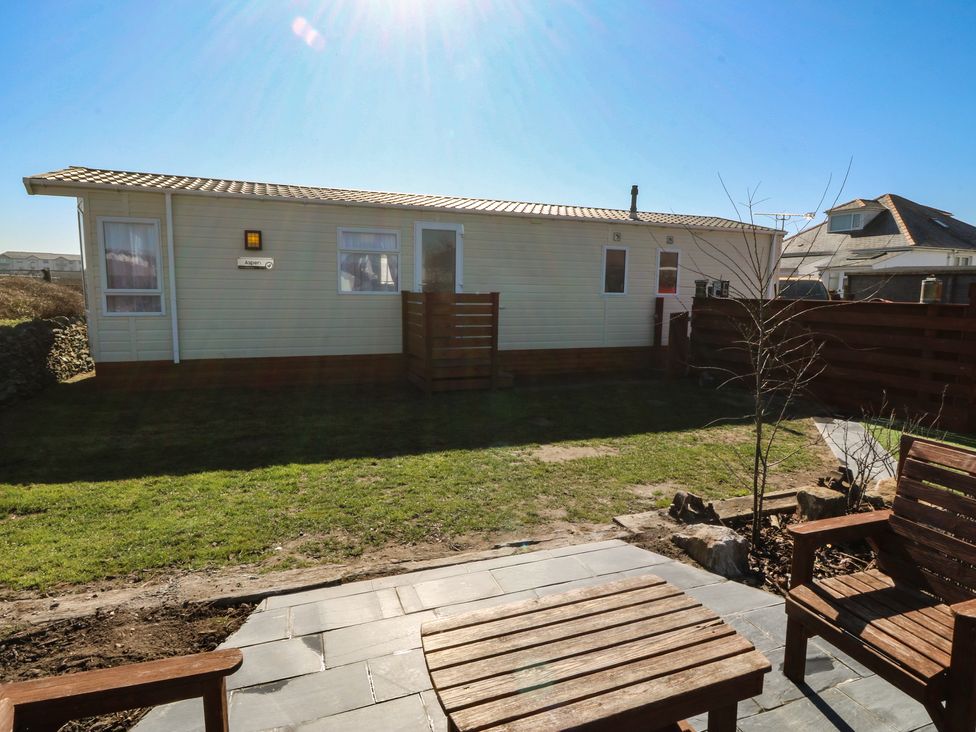 A garden with a wooden chair and a small table at Pheasant Lodge in Holyhead
