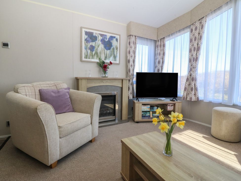A living room with an armchair and television at Pheasant Lodge in Holyhead