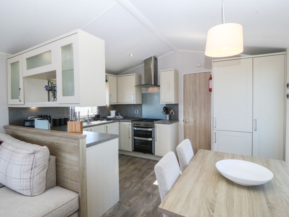 A kitchen with appliances and table at Pheasant Lodge in Holyhead