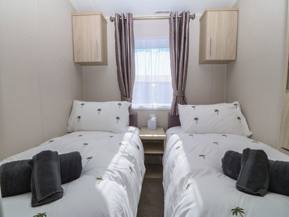 A bedroom with two beds and a window at Pheasant Lodge in Holyhead