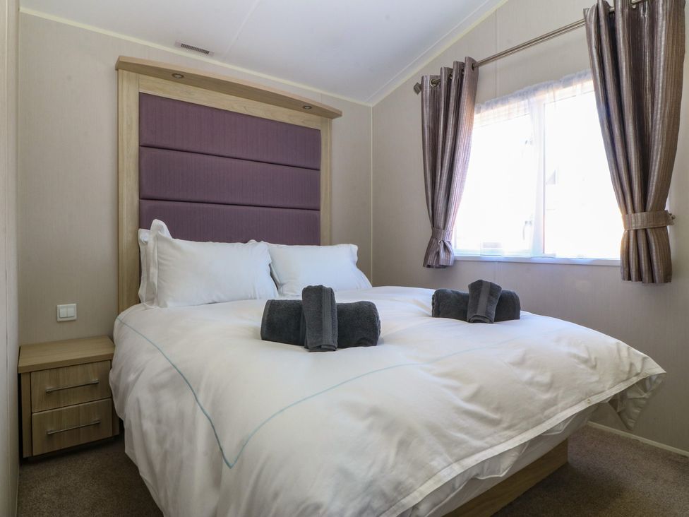 A bedroom with a double bed and a window at Pheasant Lodge in Holyhead