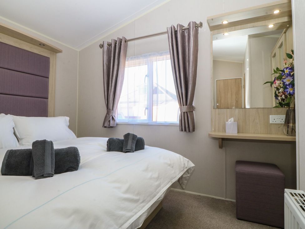 A bedroom with a bed and dressing table at Pheasant Lodge in Holyhead