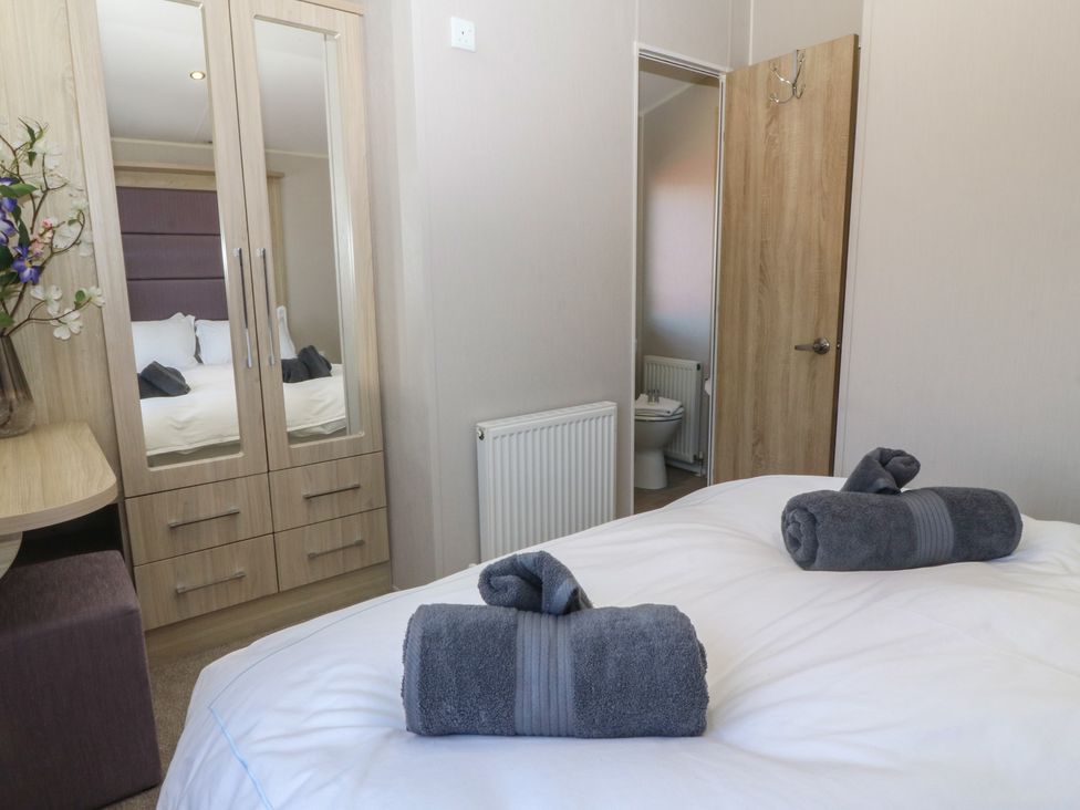 A bedroom with a bed and towels at Pheasant Lodge in Holyhead