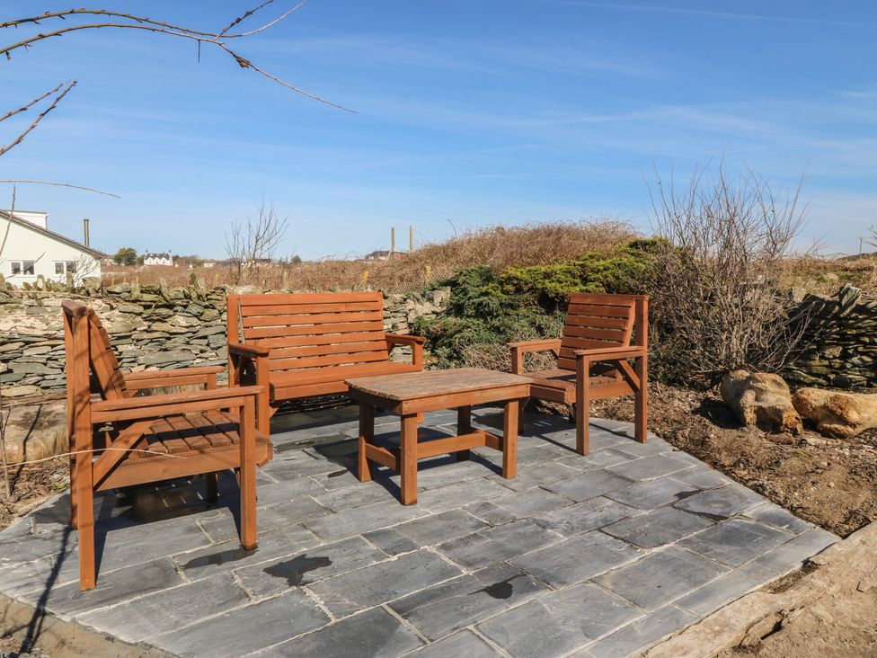 An outdoor seating area with wooden furniture at Pheasant Lodge in Holyhead