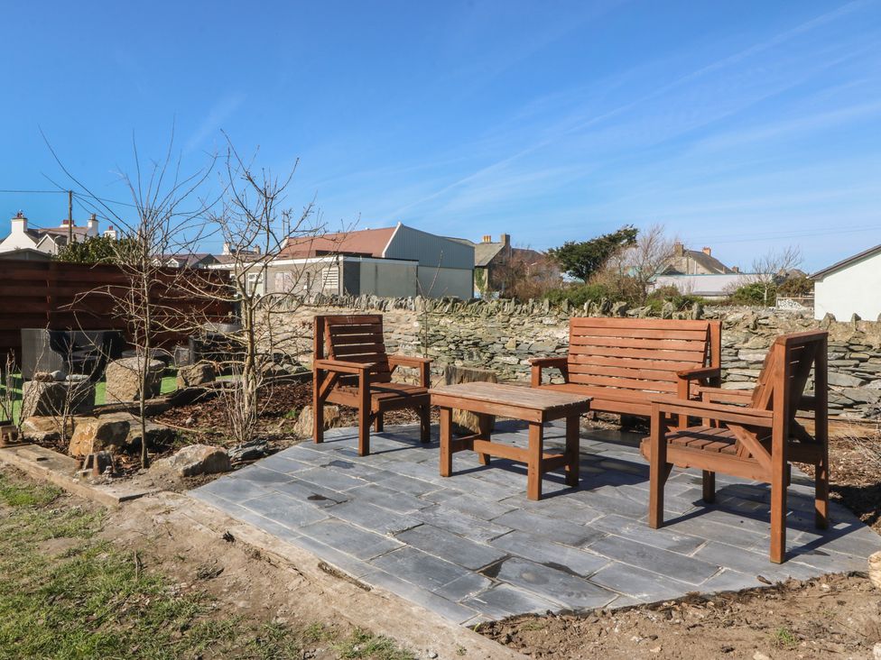 A garden with wooden seating and a table at Pheasant Lodge in Holyhead