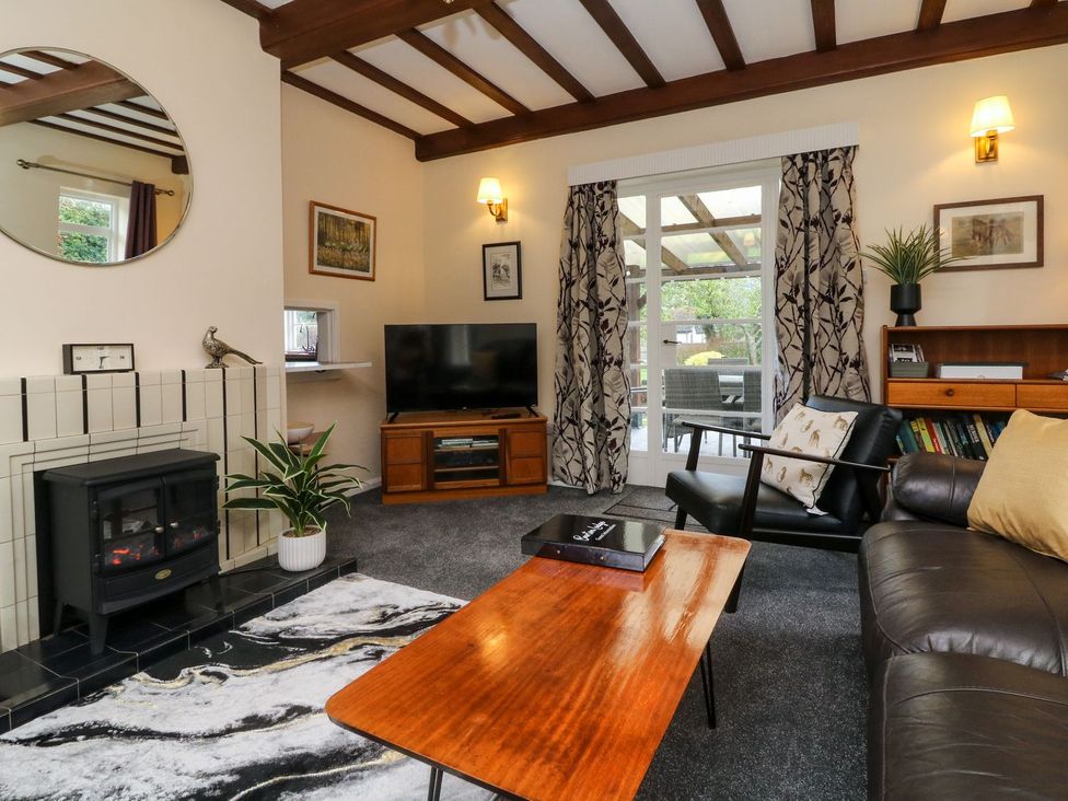 A living room with a fireplace and TV at Barton Lodge in Porlock