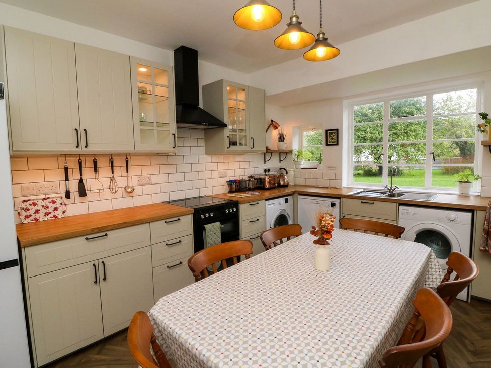 A kitchen with a stove and table at Barton Lodge in Porlock