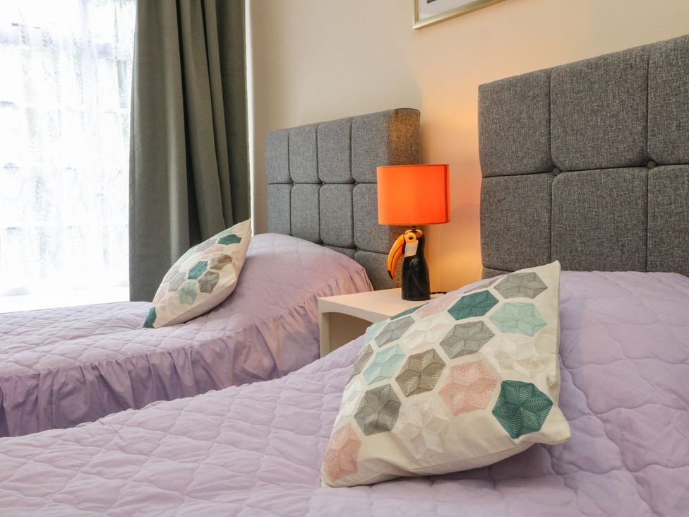 A bedroom with two beds and a lamp on a nightstand at Barton Lodge in Porlock