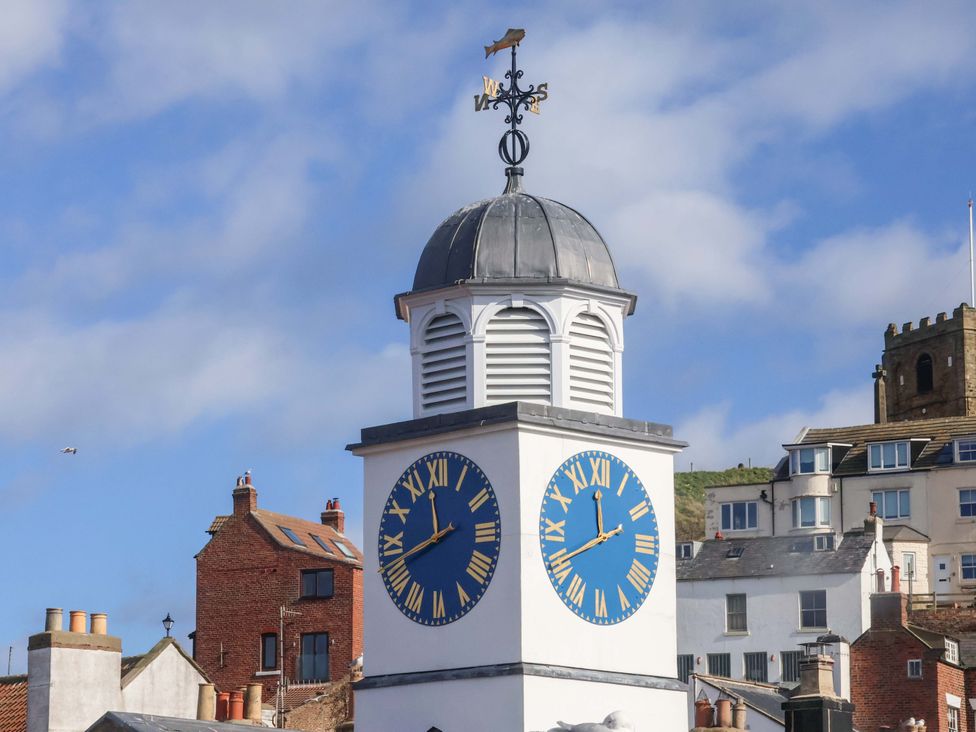 A clock tower with a weather vane and blue sky at The Four Views in Whitby
