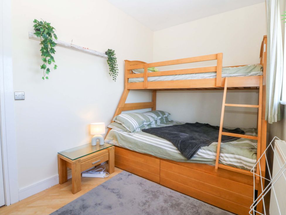 A bedroom with a bunk bed and side table at Snowdonia View in Pwllheli